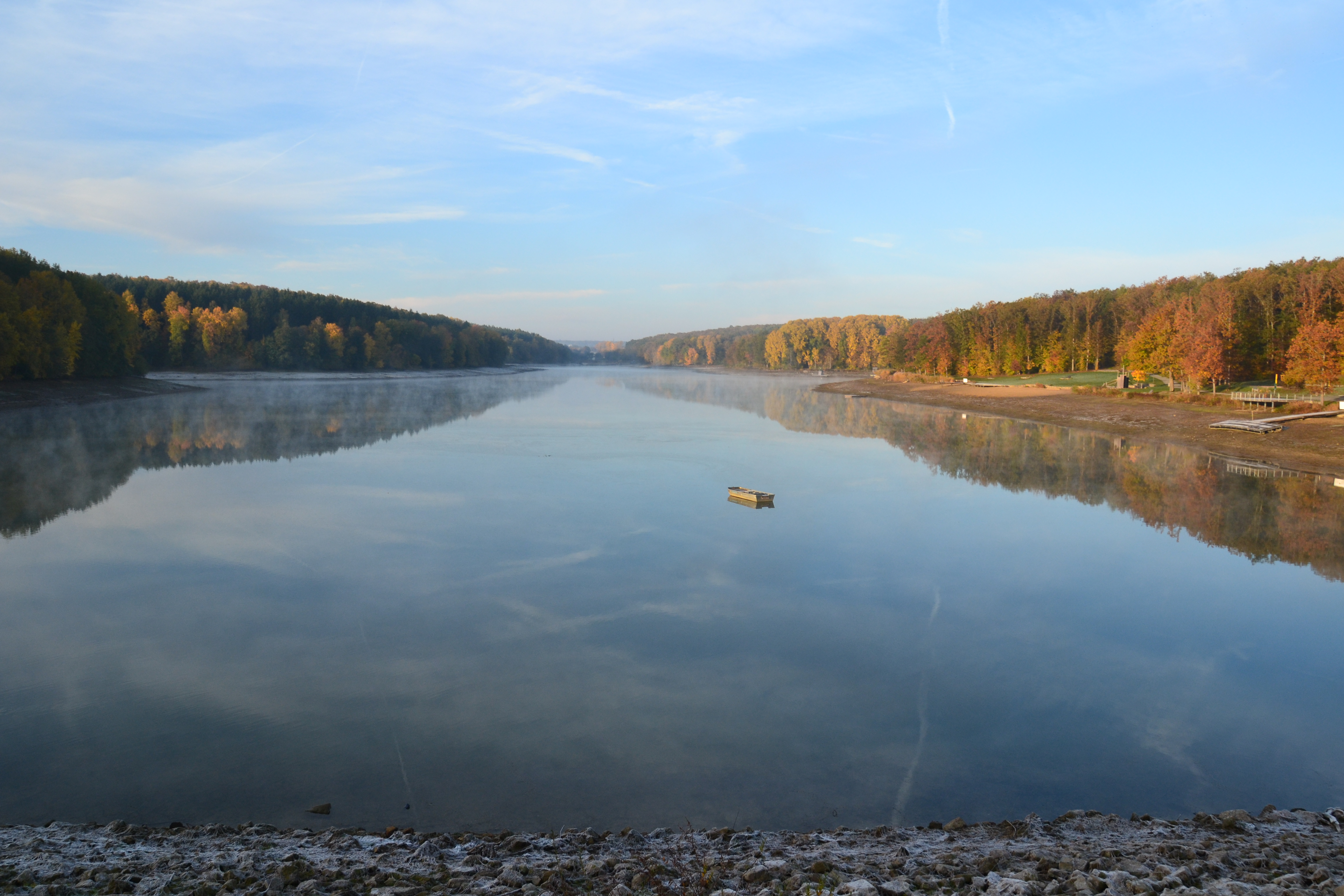 Morgendlicher Blick vom Hauptdamm auf den See mit einem einsamen Boot